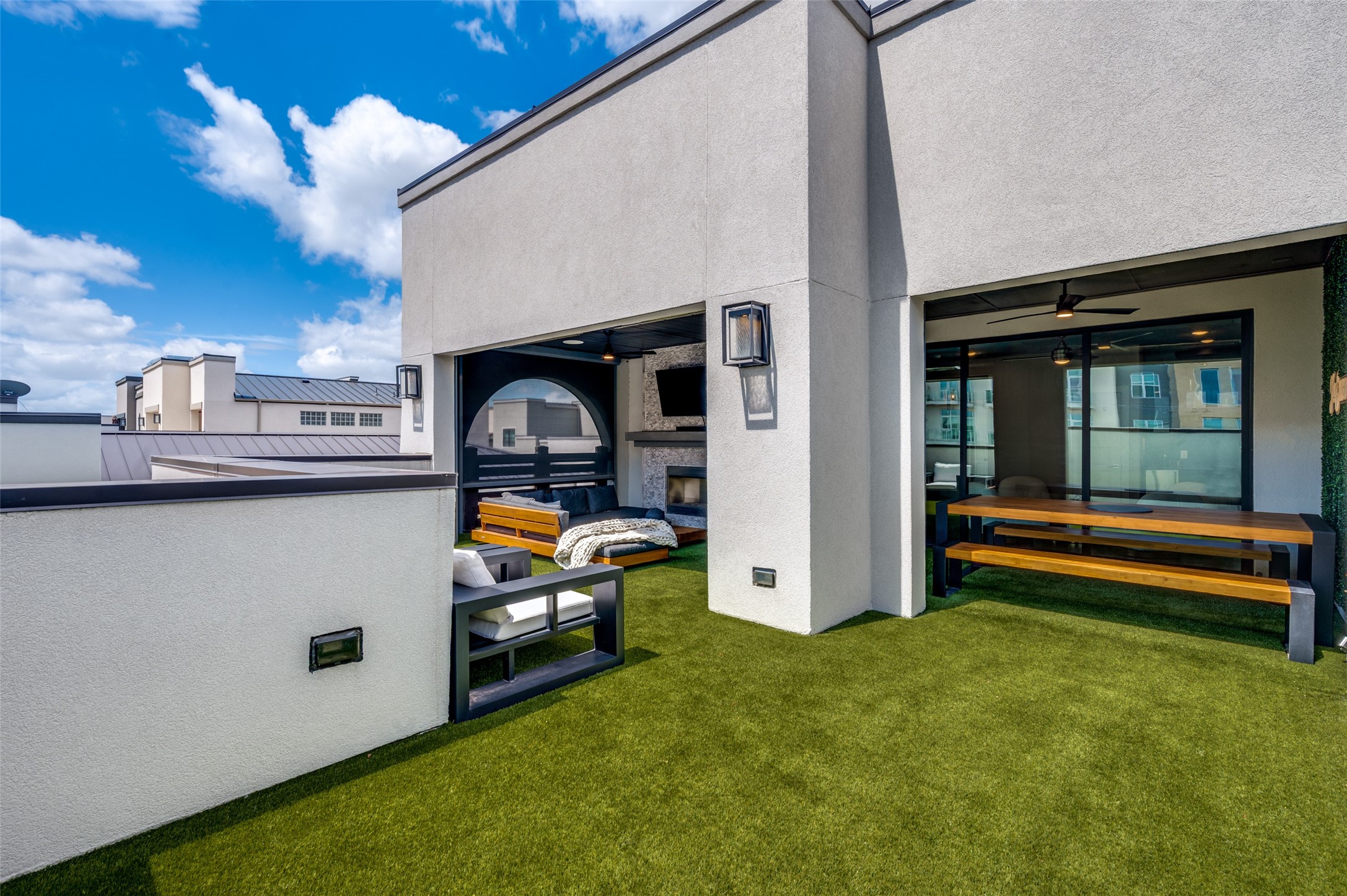 Third-floor rooftop terrace with turf, open sky, and covered dining at 7820 Merit Lane