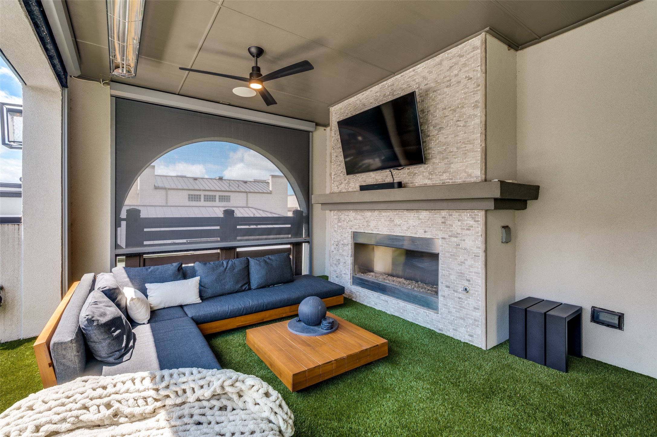 Covered third-floor terrace lounge with a fireplace, television, and seating at 7820 Merit Lane